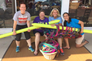 Friends have fun with a set of giant knitting needles at Fiber Circle.